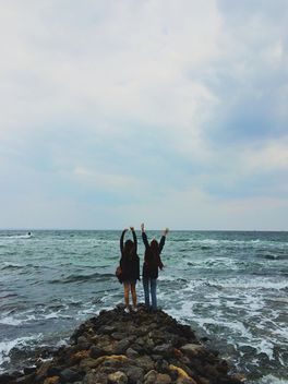 Two happy girls on the stones in the sea - бесплатный image #271689