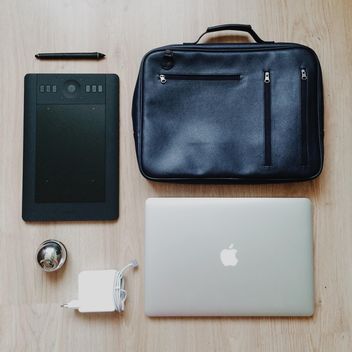 Tablet computer, e-book and black bag over wooden background - бесплатный image #271729
