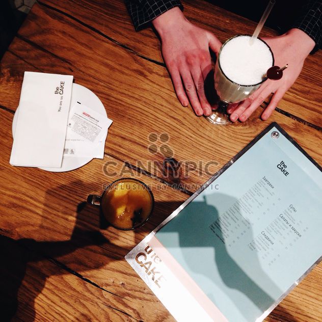 Hands and glass of milk shake on wooden table - image #346569 gratis