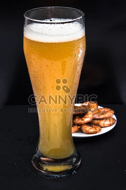 unfiltered cold foamy beer in a tall glass with a snack of fried shrimp - image #381019 gratis