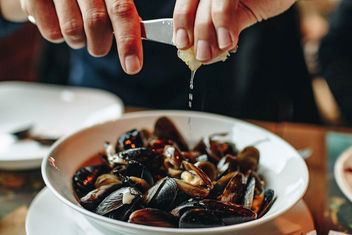 Hands squeezing lemon over plate with mussels. - Kostenloses image #452879