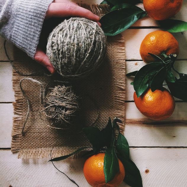 Skeins of wool and tangerines on white wooden background - Free image #136259