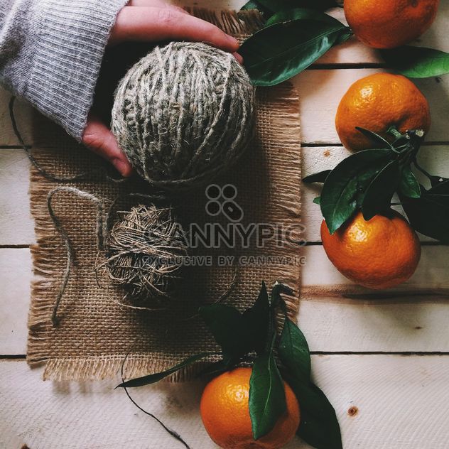 Skeins of wool and tangerines on white wooden background - Free image #136259
