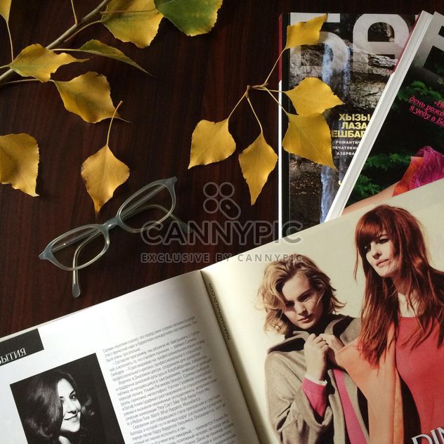 Magazines, glasses and autumn leaves on wooden table - image #182769 gratis