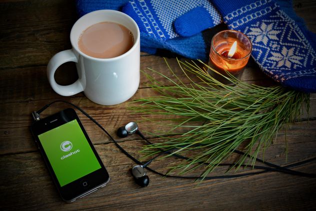Candle, iPhone with earphones and Clashot logo and cup of coffee over wooden background - image gratuit #182789 