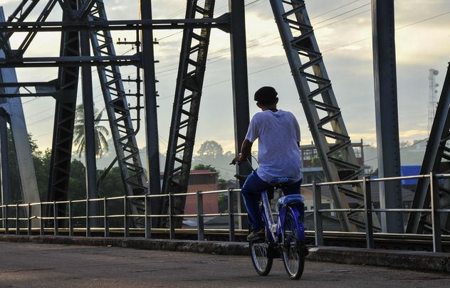 Man riding a bicycle across a bridge - бесплатный image #186389