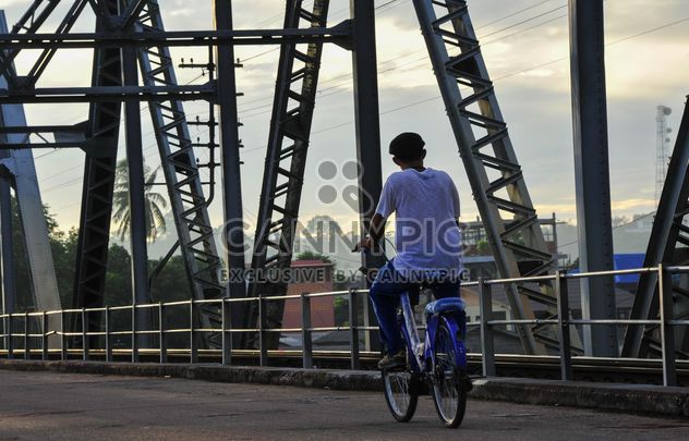 Man riding a bicycle across a bridge - image #186389 gratis