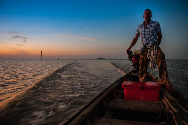 Fisherman in boat on sea at sunset - image #186589 gratis