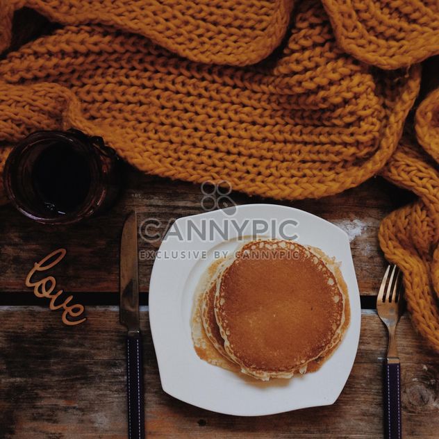 Pancakes in plate, jam and knitted scarf on wooden background - Free image #198379