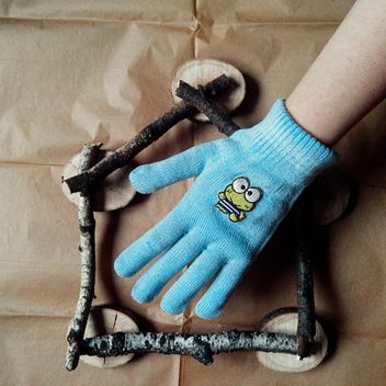 Hand in blue glove and house made of wooden sticks on beige paper background - бесплатный image #272239