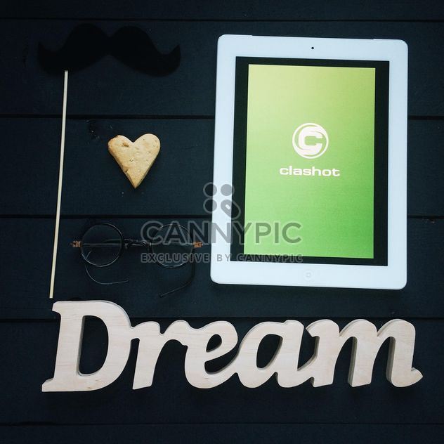 Tablet computer with Clashot logo and accessories on dark wooden background - image #329309 gratis