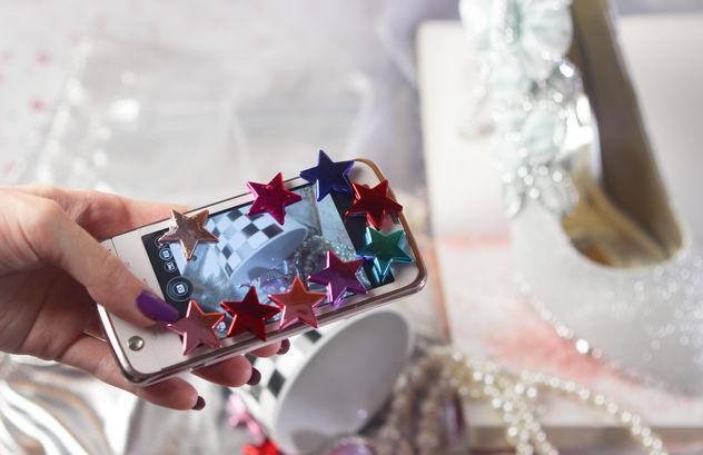 Smartphone decorated with tinsel in woman hands - бесплатный image #342189