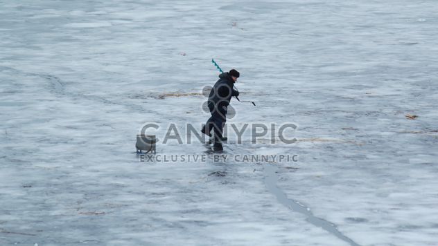 Fisherman during winter fishing on frozen river - Free image #344629