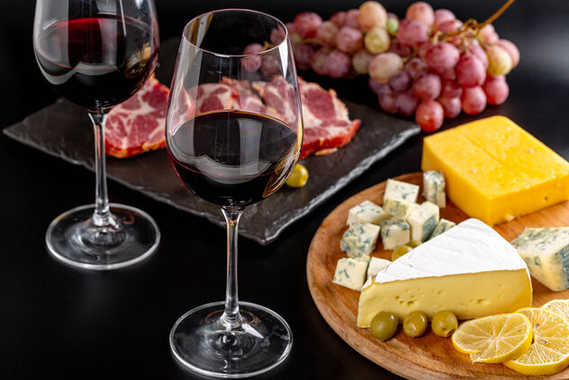 Glasses of red wine on a dark background with various delicious snacks - Free image #475899