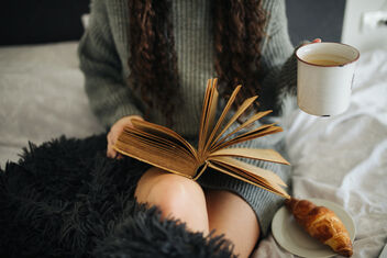A young woman reading a book and holding cup of coffee indoors. - Kostenloses image #478139